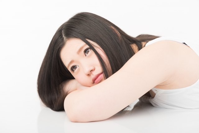 テーブルにうつ伏せて考え込む女性